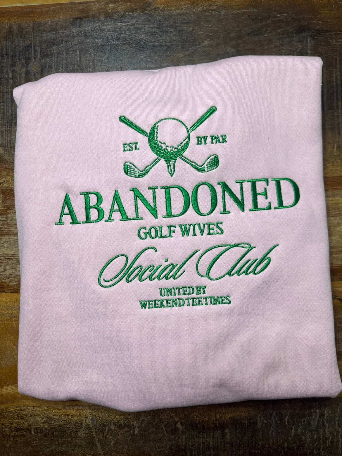 Light pink Gildan sweatshirt with green Abandoned Golf Wives Social Club embroidery