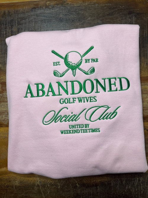 Light pink Gildan sweatshirt with green Abandoned Golf Wives Social Club embroidery