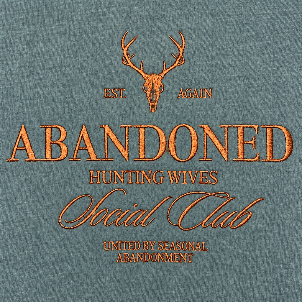 Close-up of copper brown Abandoned Hunting Wives Social Club embroidery on Blue Spruce sweatshirt